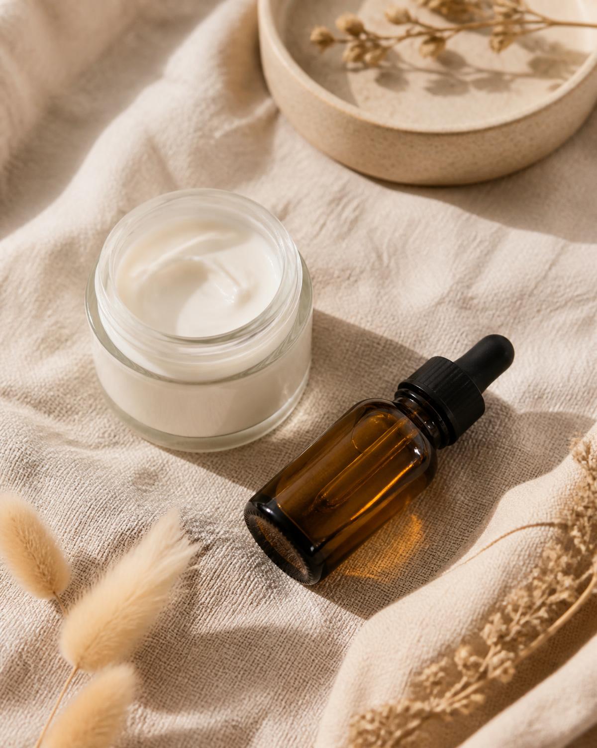 Cream jar and dropper serum styled on linen for a skincare feature